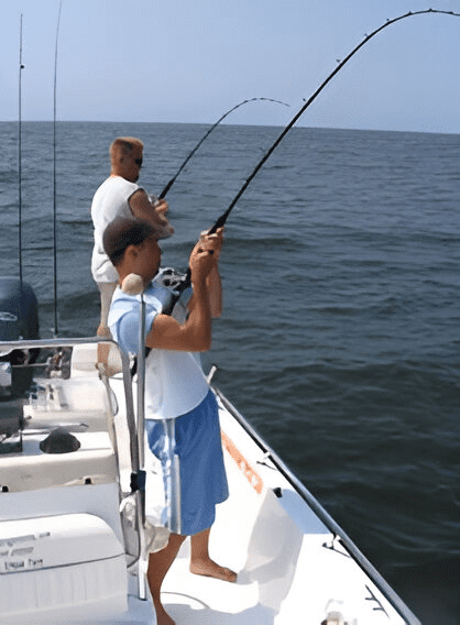 Two men fishing on a boat in the ocean.