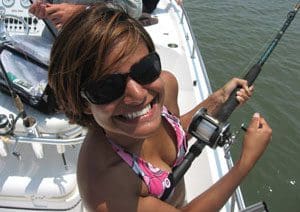 A woman holding onto a fishing rod while sitting on the boat.